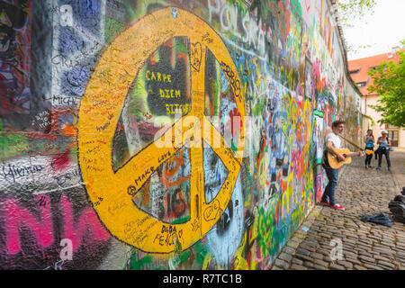 Prague John Lennon Wall, view of a busker playing a guitar alongside the John Lennon Wall in the Mala Strana district of Prague, Czech Republic. Stock Photo