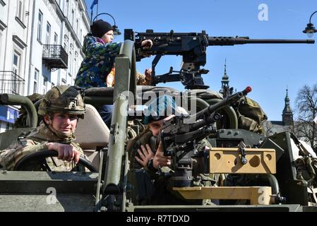 A British soldier, gives a tour of a Jackal Light Armored Vehicle to local citizens at a vehicle static display in Piotrkow Trybunalski, Poland, during a stop on the Battle Group Poland convoy, March 28, 2017. The contingency of U.S., United Kingdom and Romanian Soldiers convoyed to Orzysz, Poland where they will integrate with the Polish 15th Mechanized Brigade, 16th Infantry Division. The battle group will be based in Poland for a six month rotation for NATO’s Enhanced Forward Presence. NATO's eFP is an allied, forward deployed defense and deterrence posture in Eastern Europe to protect and  Stock Photo