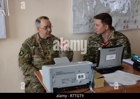 Lt. Col. James Becker, 352nd Civil Affairs Command, discusses civil military operations with a Kazakhstani soldier of the Kazakhstan Peacekeeping Battalion during day two of Steppe Eagle Koktem, Apr. 2, 2017, at Illisky Training Center, Kazakhstan. Stock Photo