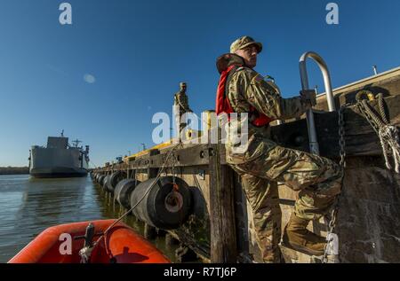 Spc. Dylan Nice, a U.S. Army Reserve watercraft operator Soldier from the 949th Transportation Company, a unit which specializes in watercraft operations, cargo and watercraft engineering, climbs a ladder from a rescue boat for a series of portraits and images depicting his unit's military occupation specialties in Baltimore, Md., on April 7-8, 2017. Stock Photo