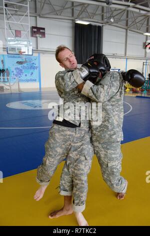 U.S. Army Staff Sgt. Philip Matherly, with SHAPE Healthcare Facility, assistant instructor, punches one of the students attempting to pass the clinch drill, during which they have to hold their opponent in order to stop his punches, for a combatives level one class taught on Chièvres Air Base, Belgium, March 22, 2017. AFNORTH Battalion, USANATO Brigade led this class open to military forces stationed in the Benelux. Stock Photo