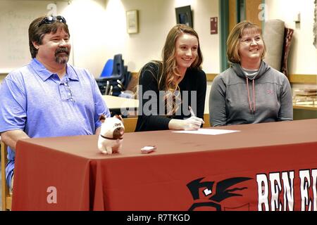 Emily Donovan, daughter of Senior Master Sgt. Rebecca Donovan, 168th Force Development superintendent, Alaska Air National Guard, signs her college letter of intent inside the Ben Eielson High School library, April 27, 2017, Eielson AFB, Alaska. Donovan, sitting between her mom and her dad Mark, will play college volleyball in Tennessee and will study exercise science and sports psychology. Stock Photo