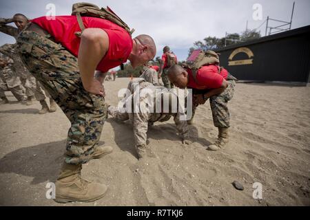 U.S. Marine Corps Sgt. Zachary O’Connor, left, and Staff Sgt. Micah S. Paguia, drill instructors with Company B, 1st Recruit Training Battalion, Recruit Training Regiment, instruct a recruit at Marine Corps Recruit Depot San Diego, Calif., April 6, 2017. O’Connor and Paguia ensured the recruit performed the exercise correctly as he participated in the dynamic warm-up portion of the event. Stock Photo