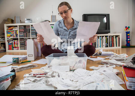 Woman sorting documents, records, invoices and receipts on the ground, for the tax return Stock Photo