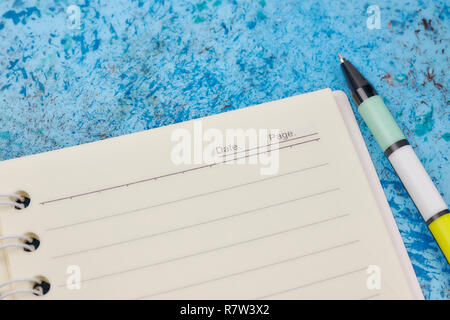 Notebook, pen, on blue abstract background. horizontal view from above. white piece of paper. Stock Photo