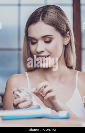 Amazing woman dipping her finger into a jar of face cream Stock Photo
