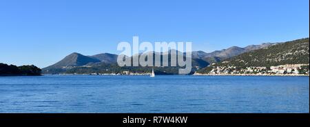 Beautiful sunny day on Mediterranean sea. Blue sky, turquoise clean sea, green hills and white sailboat in background.  Dubrovnik, Croatia Stock Photo