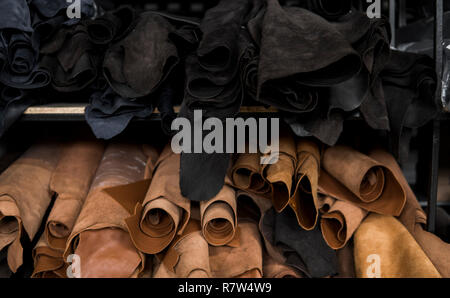 Different pieces of leather in a rolls. The pieces of the colored leathers. Rolls of natural brown and black and other leather. Raw materials for manu Stock Photo