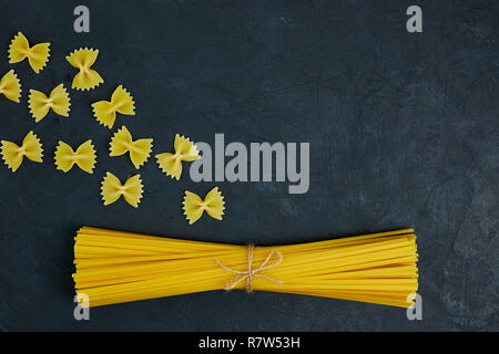 Uncooked pasta tied with a rope on concrete against black background. copy space. view from above. Stock Photo