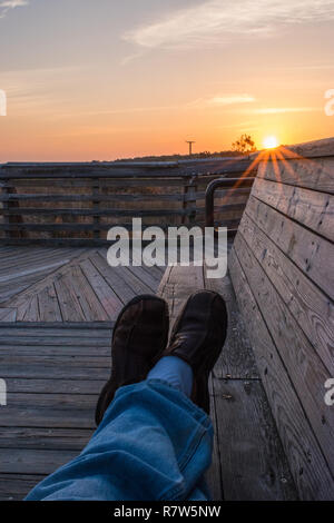 Feet up on bench enjoying the outdoors in the morning oceanfront sunshine Stock Photo