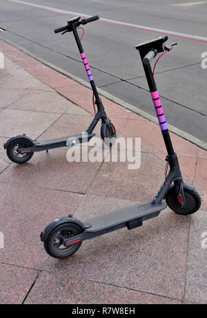 Two Lyft dockless electric scooters for pay-per-minute hire on sidewalk in Denver, Colorado, USA Stock Photo