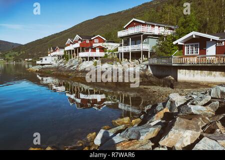 rorbuer - traditional norwegian red wooden house to stand at the lakeside and mountains in the distance, norway Stock Photo