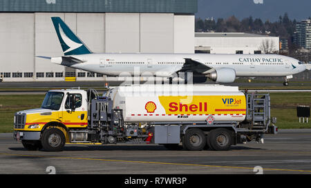 Richmond, British Columbia, Canada. 6th Dec, 2018. A Shell Aviation fuel truck drives along the tarmac at Vancouver International Airport. In the background a Cathay Pacific Airways Boeing 777-300ER taxies to its take-off position. Credit: Bayne Stanley/ZUMA Wire/Alamy Live News Stock Photo