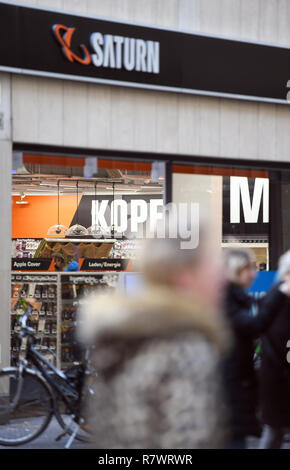 10 December 2018, North Rhine-Westphalia, Köln: Passers-by pass by a branch of the Saturn retail chain. Photo: Henning Kaiser/dpa Stock Photo