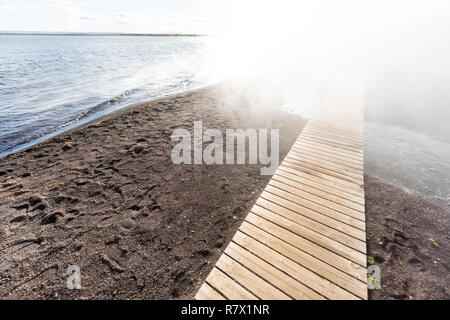 Laugarvatn lake in south Iceland on Golden Circle, shore water closeup Hot Springs Geothermal area, sunny day, steam vapor hot mist and wooden boardwa Stock Photo