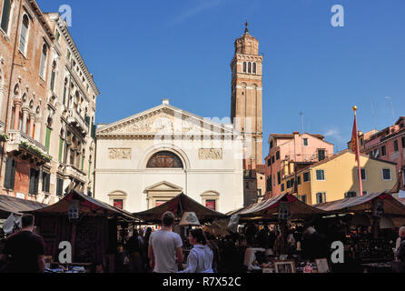 San Maurizio church and craft market in Campo San Maurizio with the leaning bell tower of Santo Stefano church behind, Venice, Italy Stock Photo