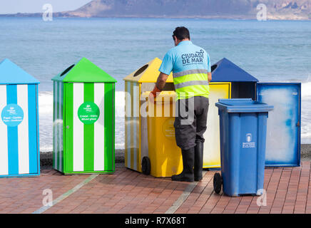 Council worker emptying colour coded waste bins for recycling plastic, paper, organic...on beach in Spain Stock Photo