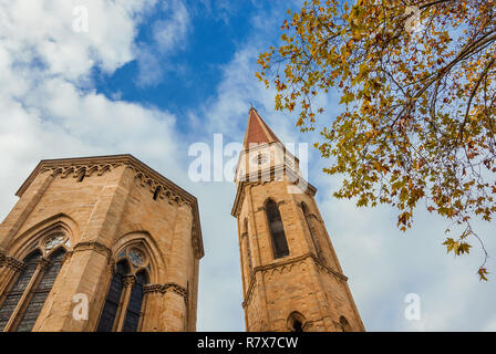 Autumn and winter in Arezzo. View of gothic cathedral apse and iconic bell tower with yellow leaves and cloudy sky Stock Photo