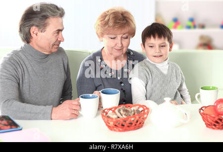 Boy Drinking Hot Chocolate and Happy Grandparents Stock Photo