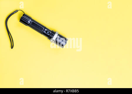 Blacc metal small tactical falshlight isoltaed on yellow background. Stock Photo