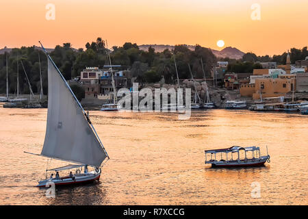 Felucca boat sailing on the Nile river at sunset in Aswan, Egypt Stock Photo