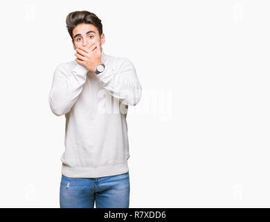 Young handsome man wearing turtleneck sweater over isolated background shocked covering mouth with hands for mistake. Secret concept. Stock Photo