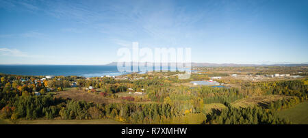 Aerial panoramic view of green fields near the Atlantic Ocean Coast during a sunny morning. Taken near New Richmond, Quebec, Canada. Stock Photo