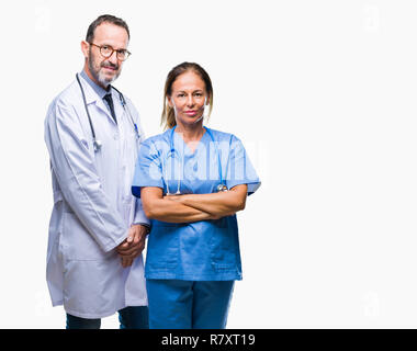 Middle age hispanic doctors partners couple wearing medical uniform over isolated background with serious expression on face. Simple and natural looki Stock Photo