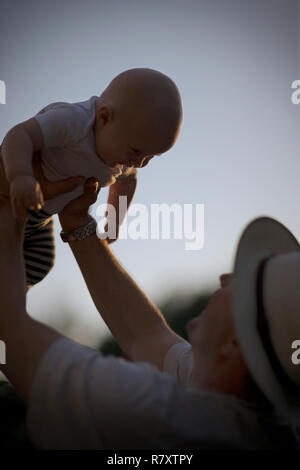 Young baby being held aloft by his father. Stock Photo