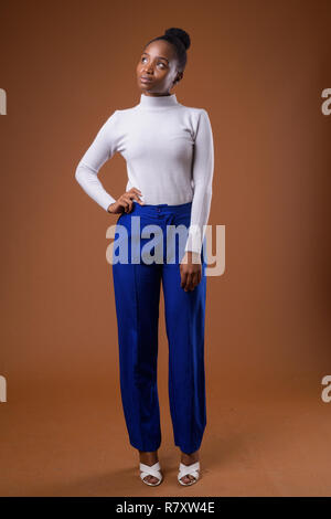 Full body portrait of young beautiful African Zulu businesswoman thinking Stock Photo