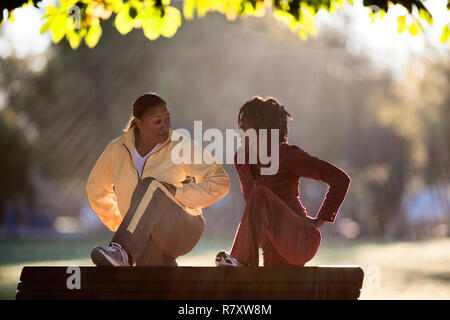 Woman stretching on park bench Stock Photo