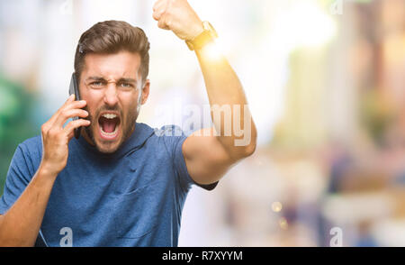 Young handsome man talking on smartphone over isolated background annoyed and frustrated shouting with anger, crazy and yelling with raised hand, ange Stock Photo