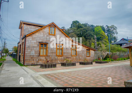 PUERTO VARAS, CHILE, SEPTEMBER, 23, 2018: Outdoor view of old wooden house building, with some trees in front, located in Puerto Varas in Chile Stock Photo