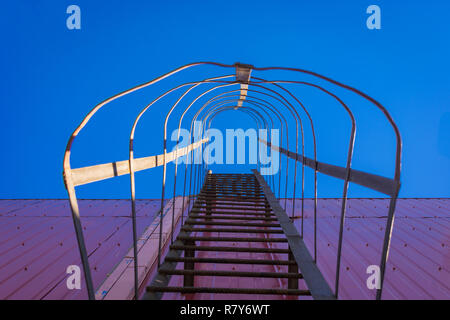 Directly below shot of metallic ladder on wall against the sky Stock Photo