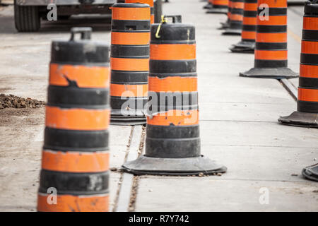 Construction barrels, north American style, on a renovation site on an asphalted street of downtown Toronto, Ontario, Canada. These plots are iconic o Stock Photo