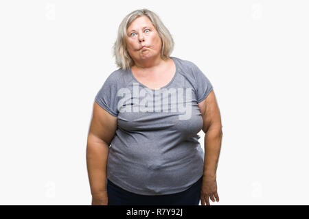 Senior plus size caucasian woman over isolated background making fish face with lips, crazy and comical gesture. Funny expression. Stock Photo