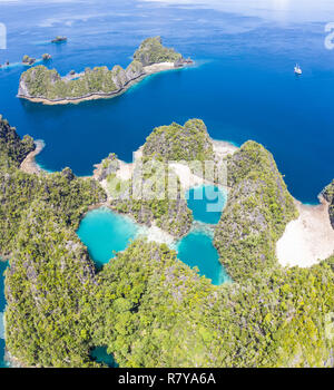 Shallow coral reefs surround remote limestone islands in Raja Ampat, Indonesia. This biodiverse region is known as the 'heart of the Coral Triangle.' Stock Photo