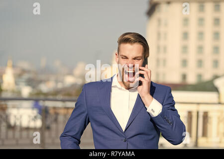 angry manager talk on smartphone. Man with mobile phone on sunny terrace. Businessman in blue suit outdoor. Business communication, new technology and sms. Modern life and business lifestyle. Stock Photo