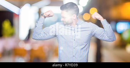 Young handsome man over isolated background showing arms muscles smiling proud. Fitness concept. Stock Photo