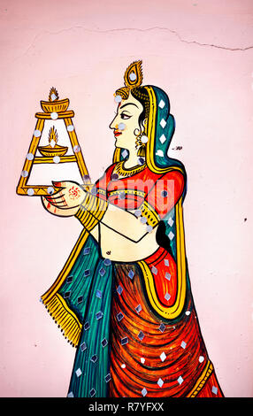 Traditional Rajasthan painting on the house wall of a woman in sari with candle in Udaipur, Rajasthan, India Stock Photo