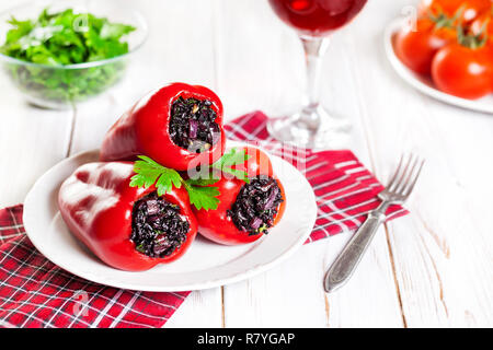 Stuffed red capsicums by black rice with vegetables on the table in restaurant Stock Photo