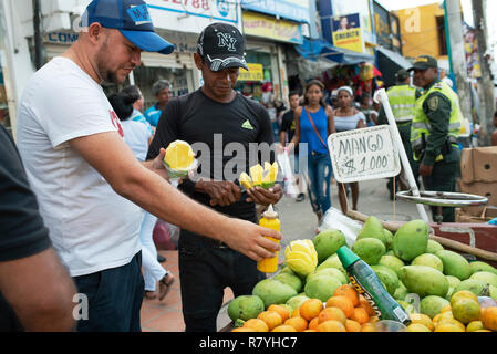 Latino fruit vendor cutting up mango (with spicy sauce and salt) at Bazurto market (Mercado Bazurto) in Cartagena de Indias, Colombia. Oct 2018 Stock Photo