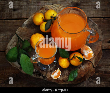 Freshly squeezed tangerine juice in a clear pitcher and tangerines Stock Photo