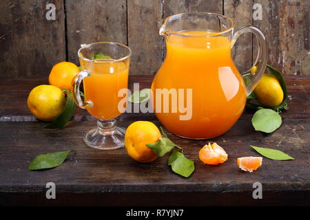 Freshly squeezed tangerine juice in a clear pitcher and tangerines Stock Photo