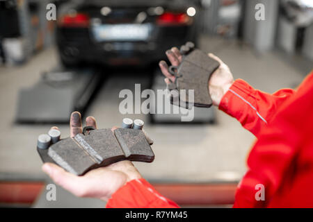 Auto mechanic holding new and used brake pads at the car service, close-up view Stock Photo