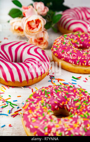 Pink donuts and rose on a wooden background. Delicious dessert. Stock Photo