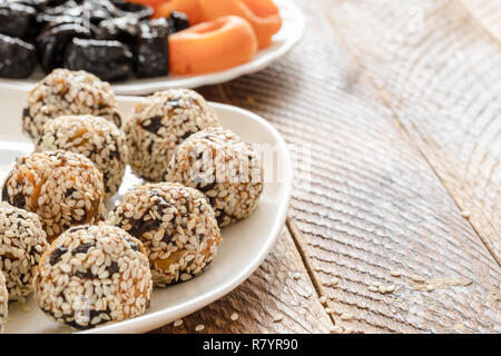 Healthy handmade energy balls made from dried fruits on white plate on wooden table. Stock Photo