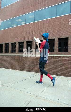 Lean student reading a book while taking a walk wearing very stylish clothing. St Paul Minnesota MN USA Stock Photo