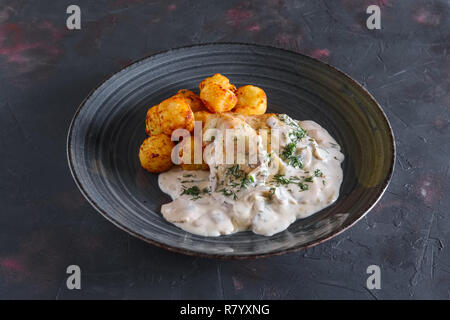 Fried potato balls and white fish fillet with creamy sauce Stock Photo
