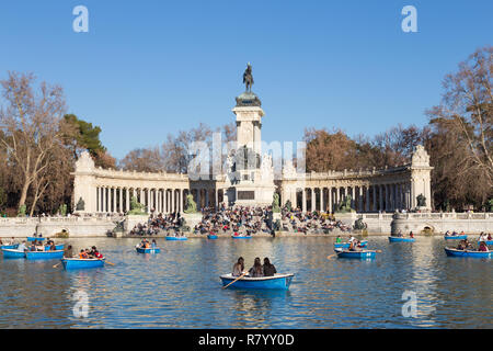 Tourists rowing traditional blue boats on lake in Retiro city park on a nice sunny winter day in Madrid, Spain. Stock Photo